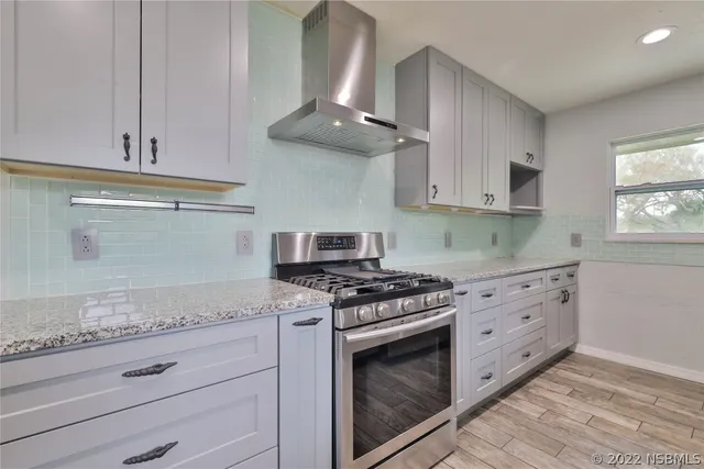 a kitchen with granite countertop a stove and a white cabinets