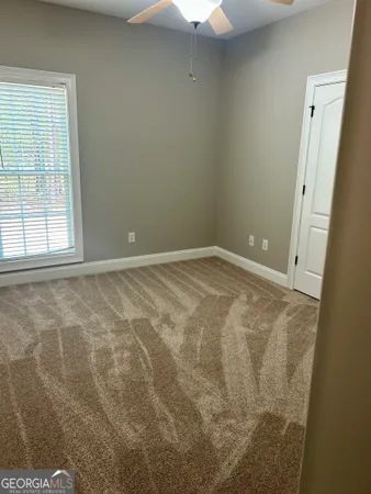 a view of an empty room with window and chandelier fan