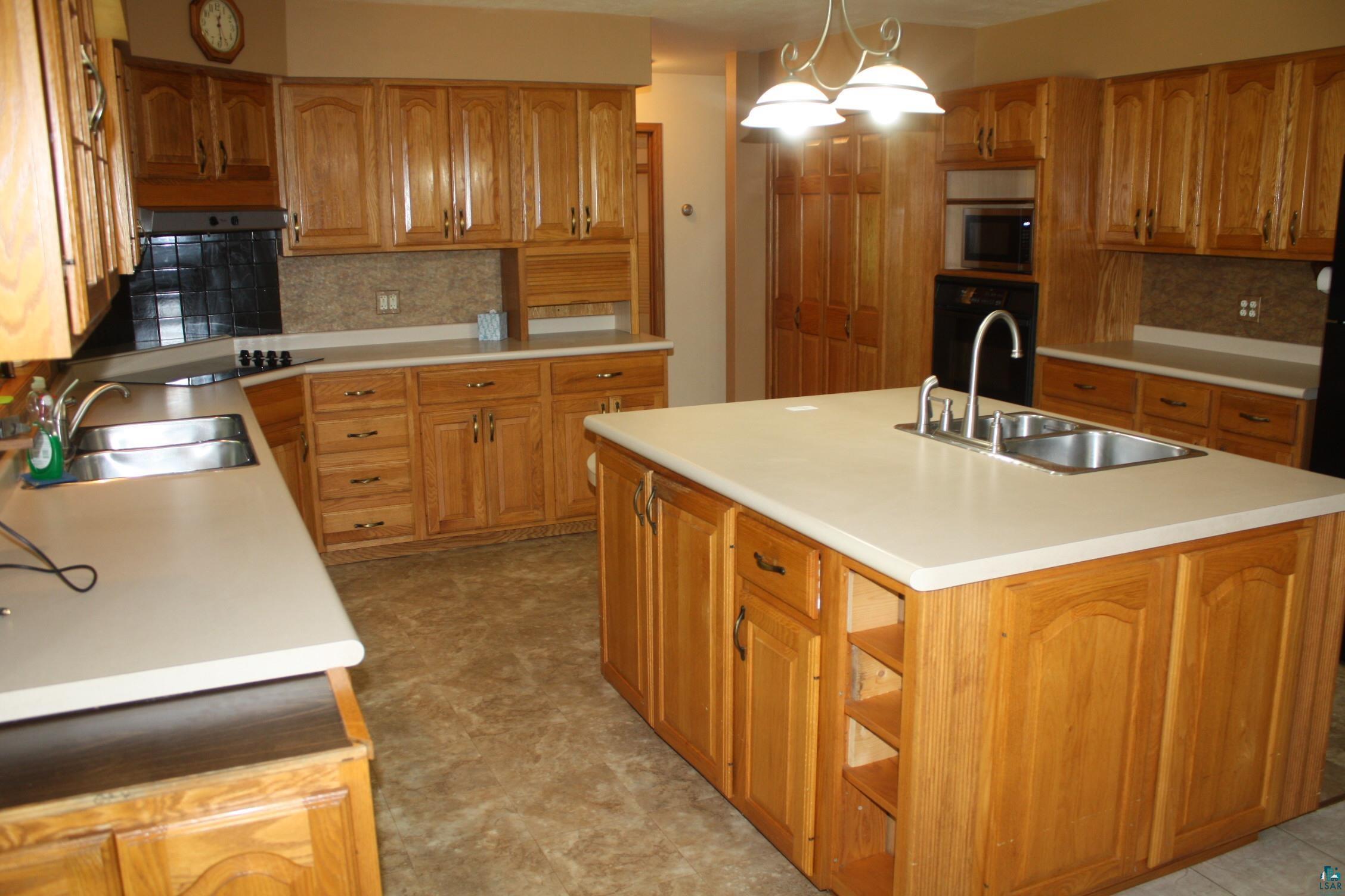 6718 East County Rd B South Range, WI 54874 - Photo 17 of 50 Kitchen with an island with sink, sink, decorative light fixtures, and tasteful backsplash