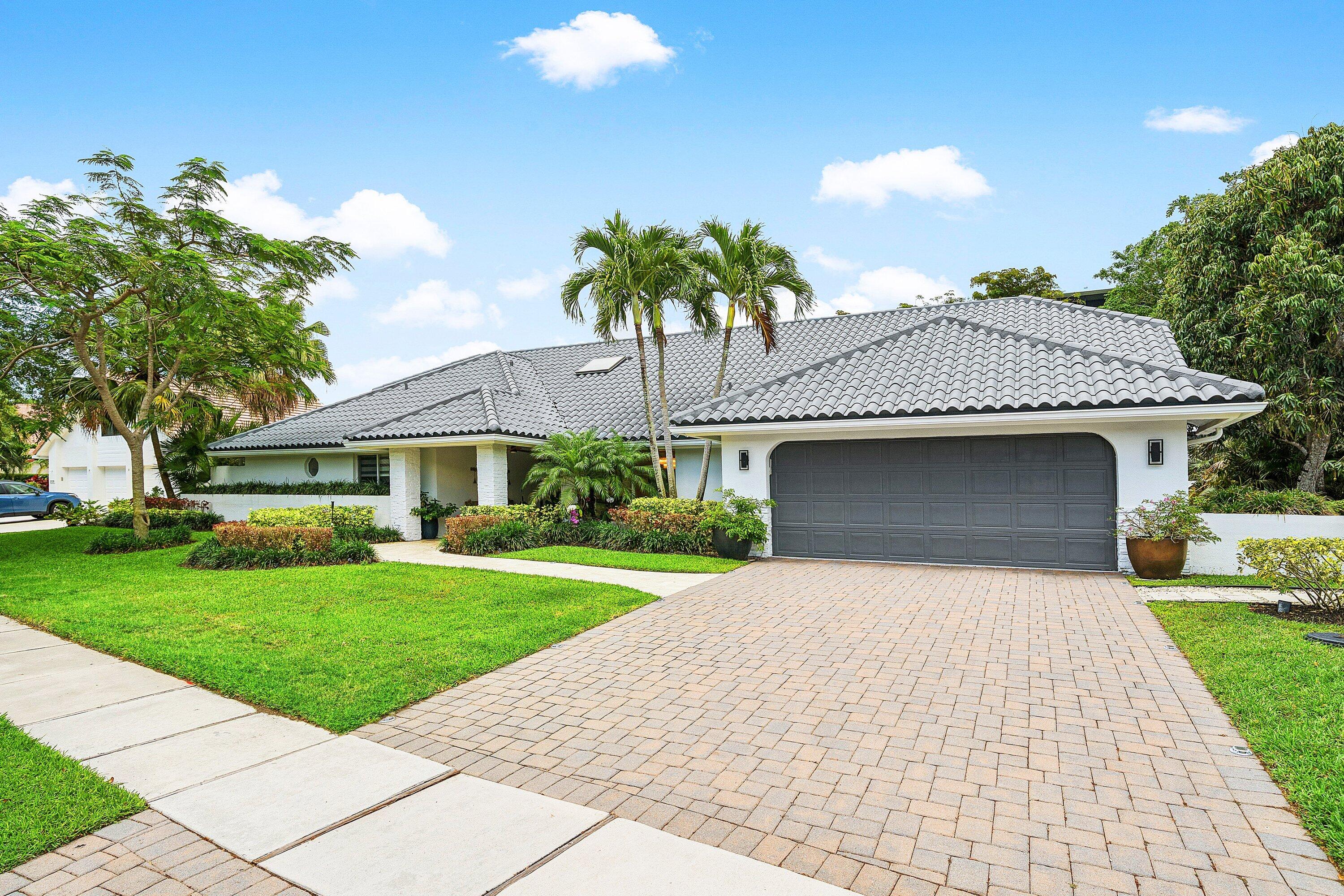 a front view of a house with a garden and trees