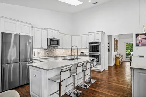 a kitchen with stainless steel appliances granite countertop a refrigerator a stove a sink a dining table and chairs