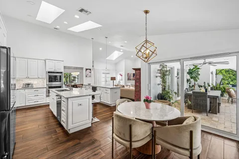 a kitchen that has a table chairs stainless steel appliances and wooden floor