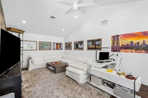 a living room with furniture a flat screen tv and a refrigerator