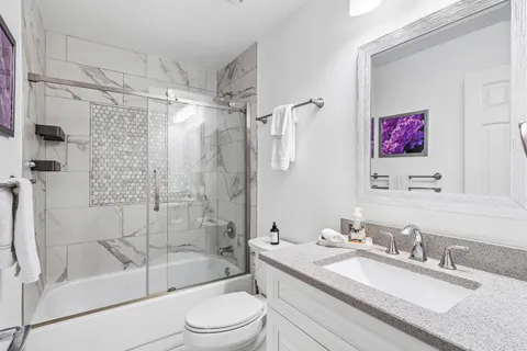 a bathroom with a granite countertop sink toilet tub and shower