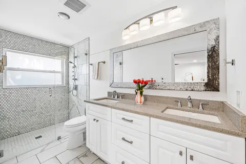 a bathroom with a granite countertop sink mirror vanity and toilet