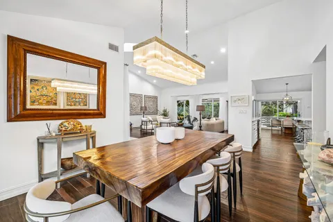 a dining room with wooden floor a chandelier a wooden table and chairs
