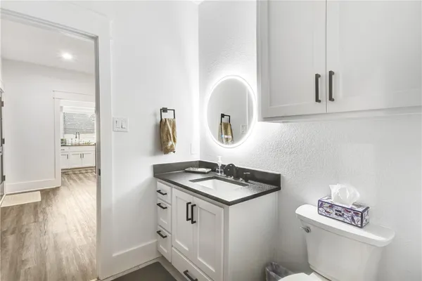 a white kitchen with sink a stove and a wooden floor