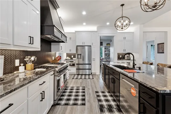 a kitchen with stainless steel appliances granite countertop a sink stove and cabinets