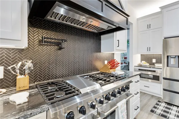 a kitchen with a stove and a white wooden cabinets