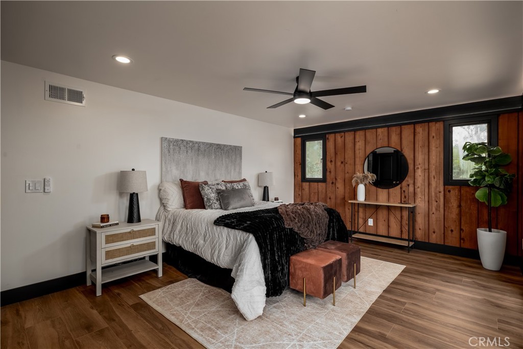 7744 West Lilac Road Bonsall, CA 92003 - Photo 33 of 60 a bedroom with a bed a couch and potted plant with wooden floor