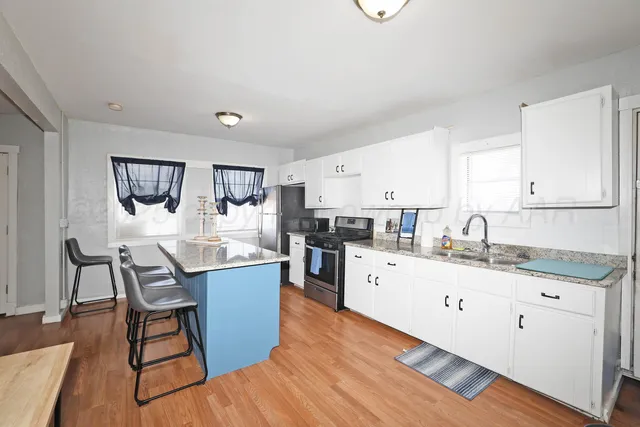 a kitchen with granite countertop kitchen island a refrigerator a stove a sink a dining table and chairs