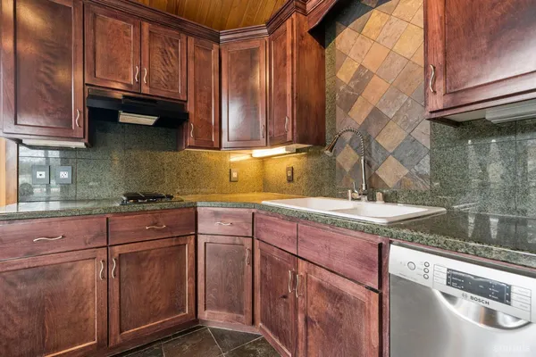 a kitchen with granite countertop a sink a stove and cabinets
