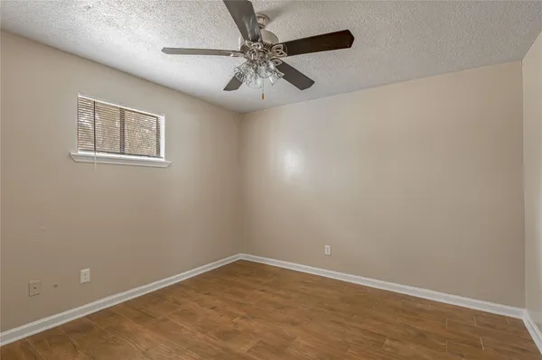 an empty room with a fan & a window
