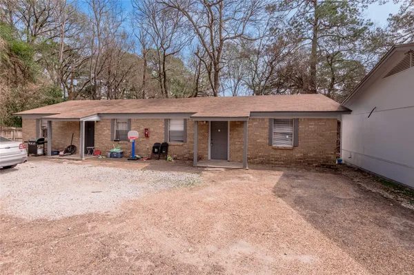 a view of a white house with a large tree and wooden fence