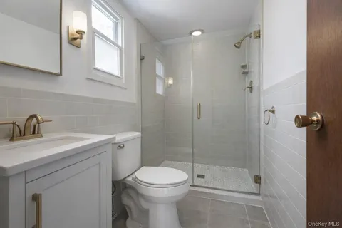 a bathroom with a shower sink vanity mirror and toilet