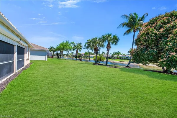 a view of a house with a big yard and palm trees