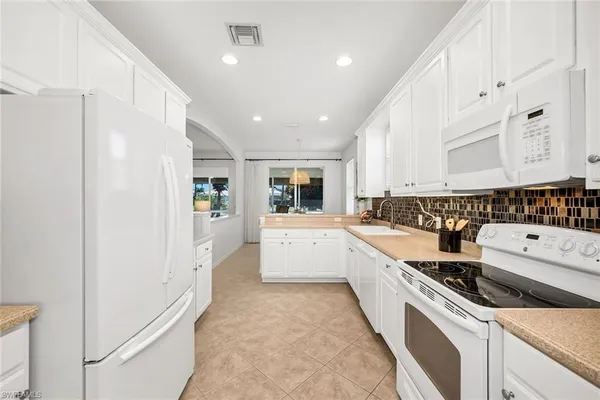 a large white kitchen with a white stove top oven and sink