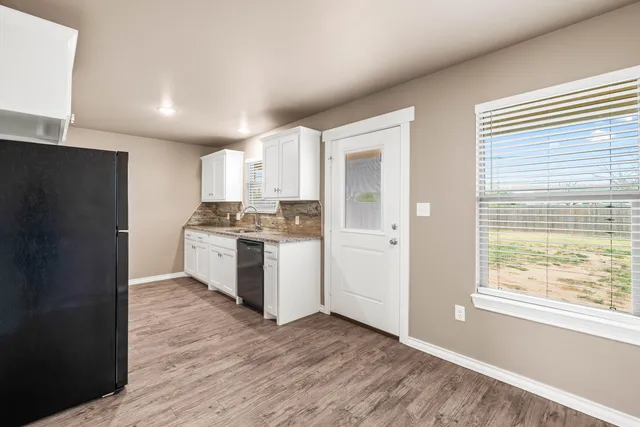 a kitchen with granite countertop a refrigerator and a stove top oven
