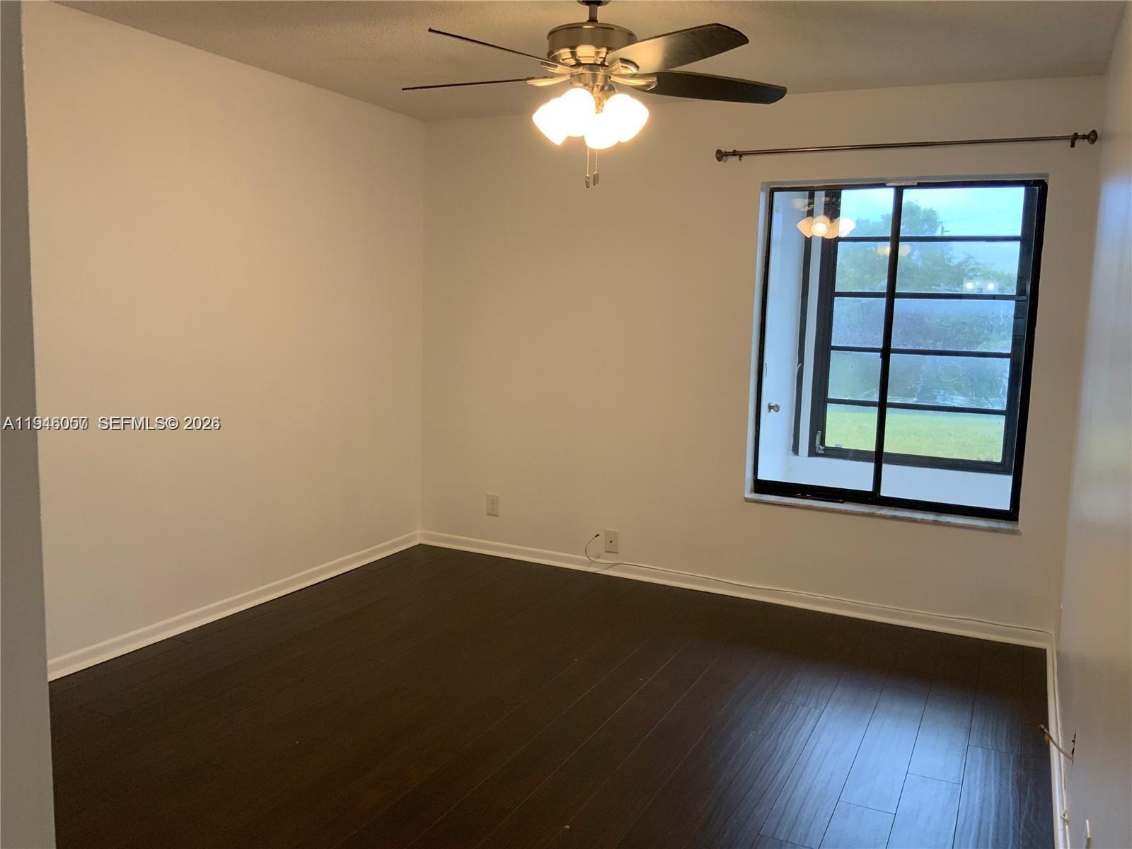 9920 Northwest 68th Place, Unit 110 Tamarac, FL 33321 - Photo 11 of 22 a view of an empty room with wooden floor and a window