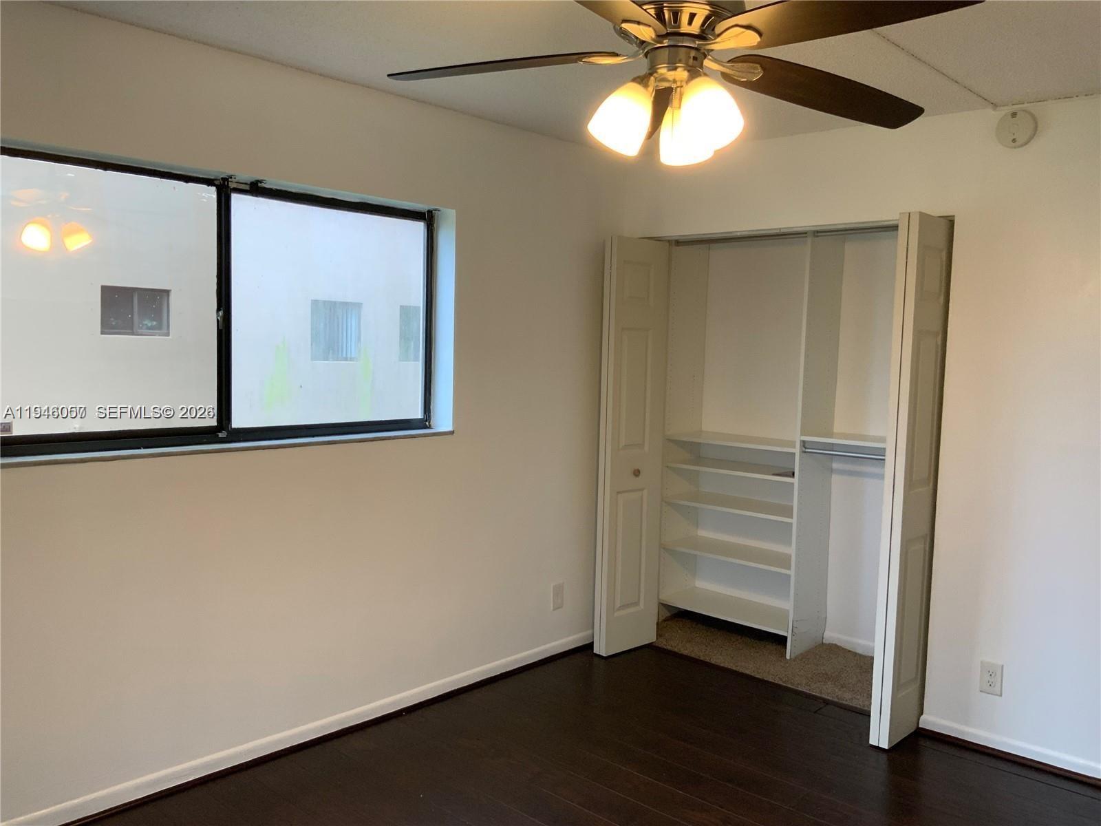 9920 Northwest 68th Place, Unit 110 Tamarac, FL 33321 - Photo 12 of 22 a view of an empty room with a window and wooden floor
