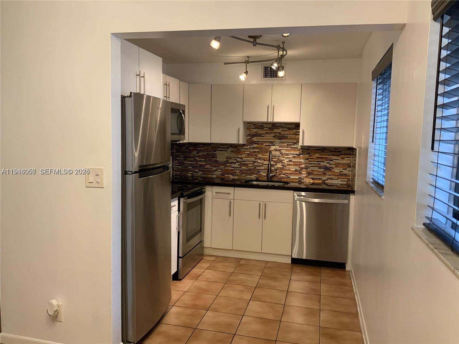 9920 Northwest 68th Place, Unit 110 Tamarac, FL 33321 - Photo 4 of 22 a kitchen with stainless steel appliances granite countertop a refrigerator and a sink