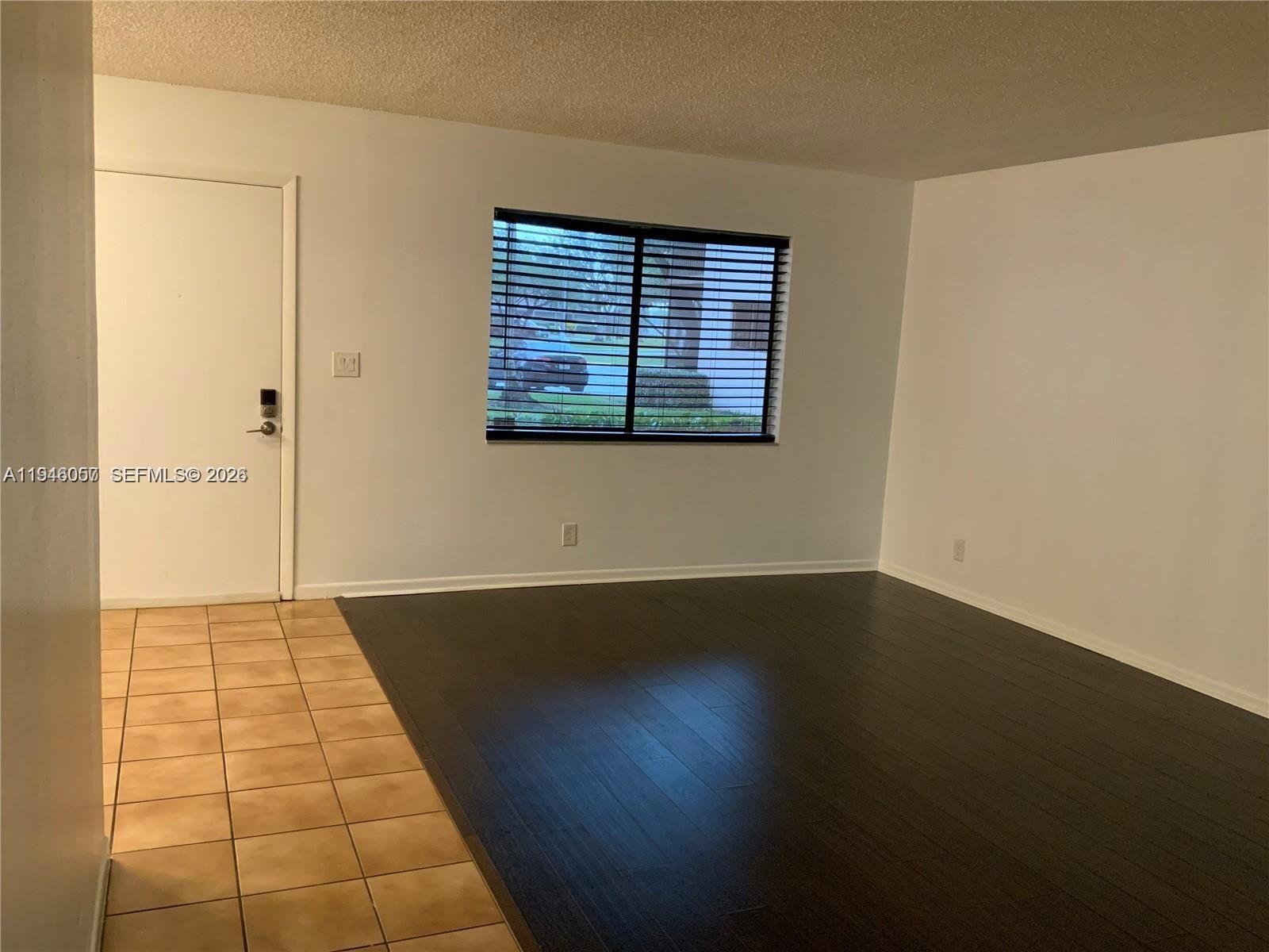 9920 Northwest 68th Place, Unit 110 Tamarac, FL 33321 - Photo 6 of 22 a view of an empty room with wooden floor and a window