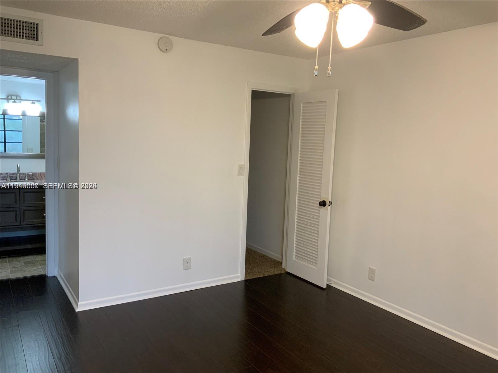 9920 Northwest 68th Place, Unit 110 Tamarac, FL 33321 - Photo 9 of 22 an empty room with wooden floor closet and windows