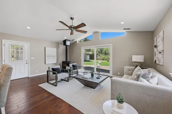 a kitchen with stainless steel appliances granite countertop a sink a stove a dining table and chairs with wooden floor