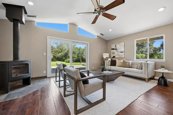 a kitchen with stainless steel appliances kitchen island granite countertop a stove a sink a refrigerator and white cabinets with wooden floor