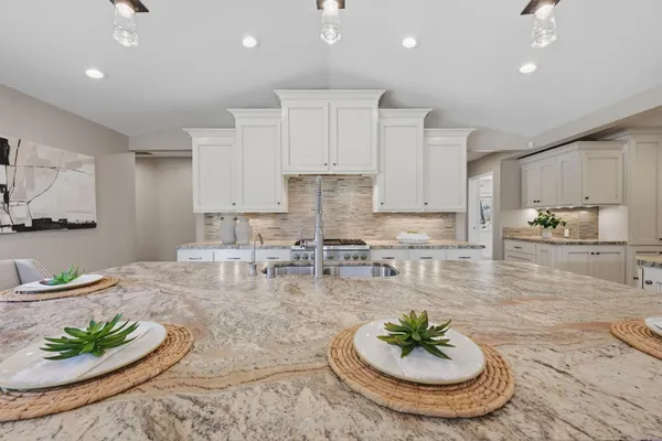 a kitchen with white cabinets and wooden floor
