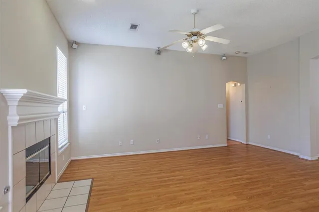 a view of an empty room with chandelier fan and fire place