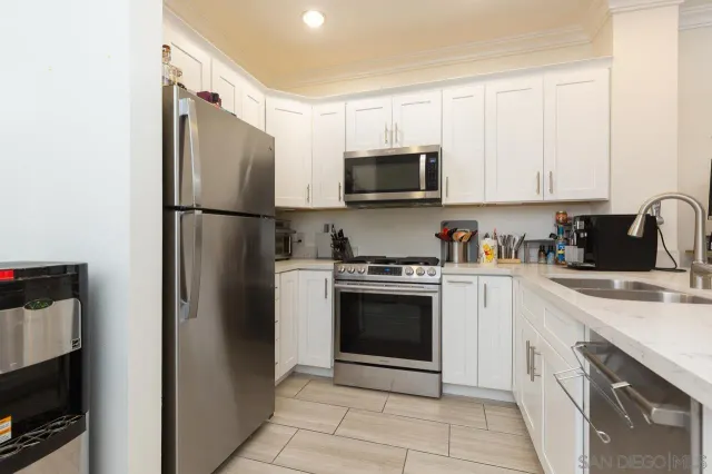 a kitchen with stainless steel appliances granite countertop a refrigerator stove a sink and white cabinets