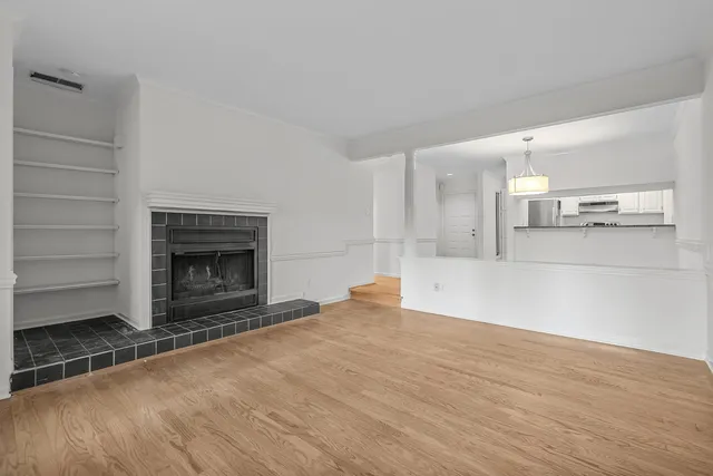 a view of kitchen and empty room with wooden floor