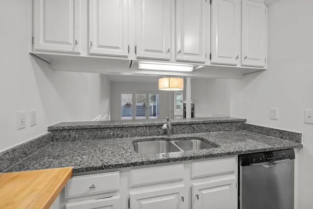 a kitchen with granite countertop white cabinets and a stove top oven