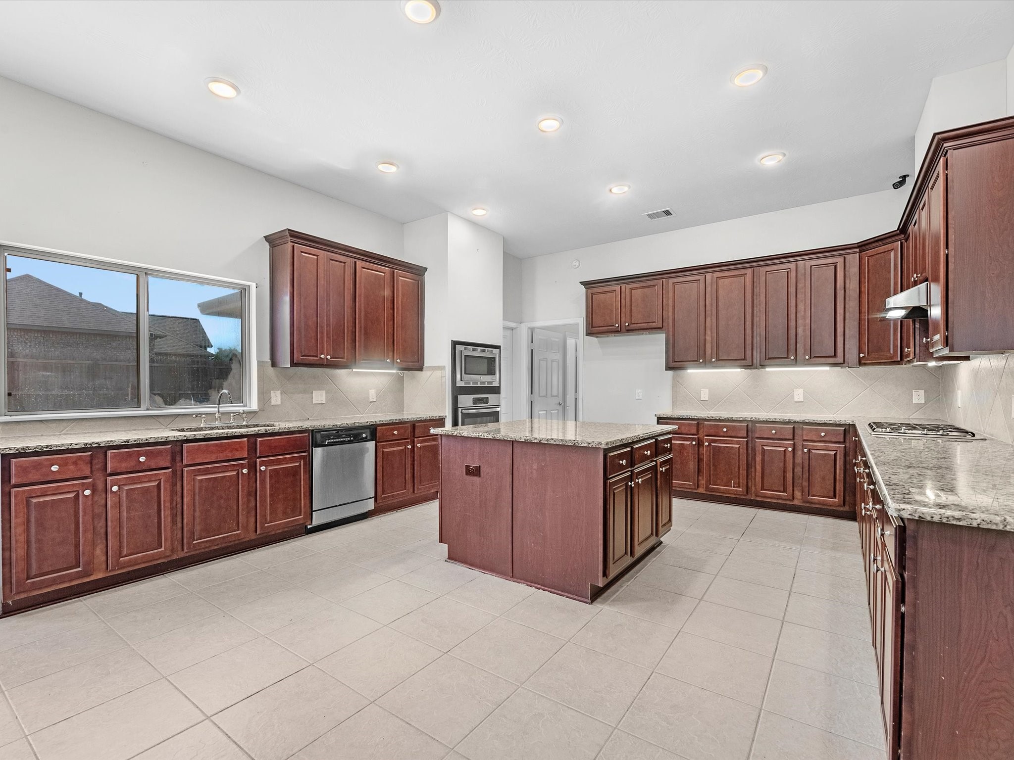 38 Palmero Way Manvel, TX 77578 - Photo 15 of 43 a kitchen with stainless steel appliances granite countertop wooden cabinets a stove a sink and a large window