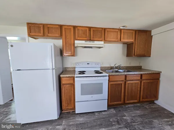 a kitchen with stainless steel appliances granite countertop a refrigerator a stove a sink and a white cabinets