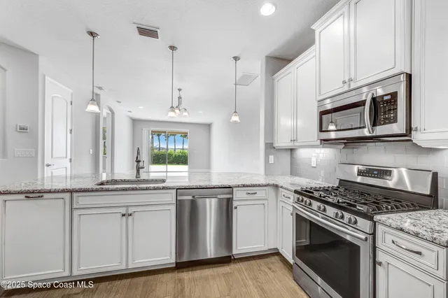 a kitchen with stainless steel appliances granite countertop a sink a stove a microwave and wooden cabinets