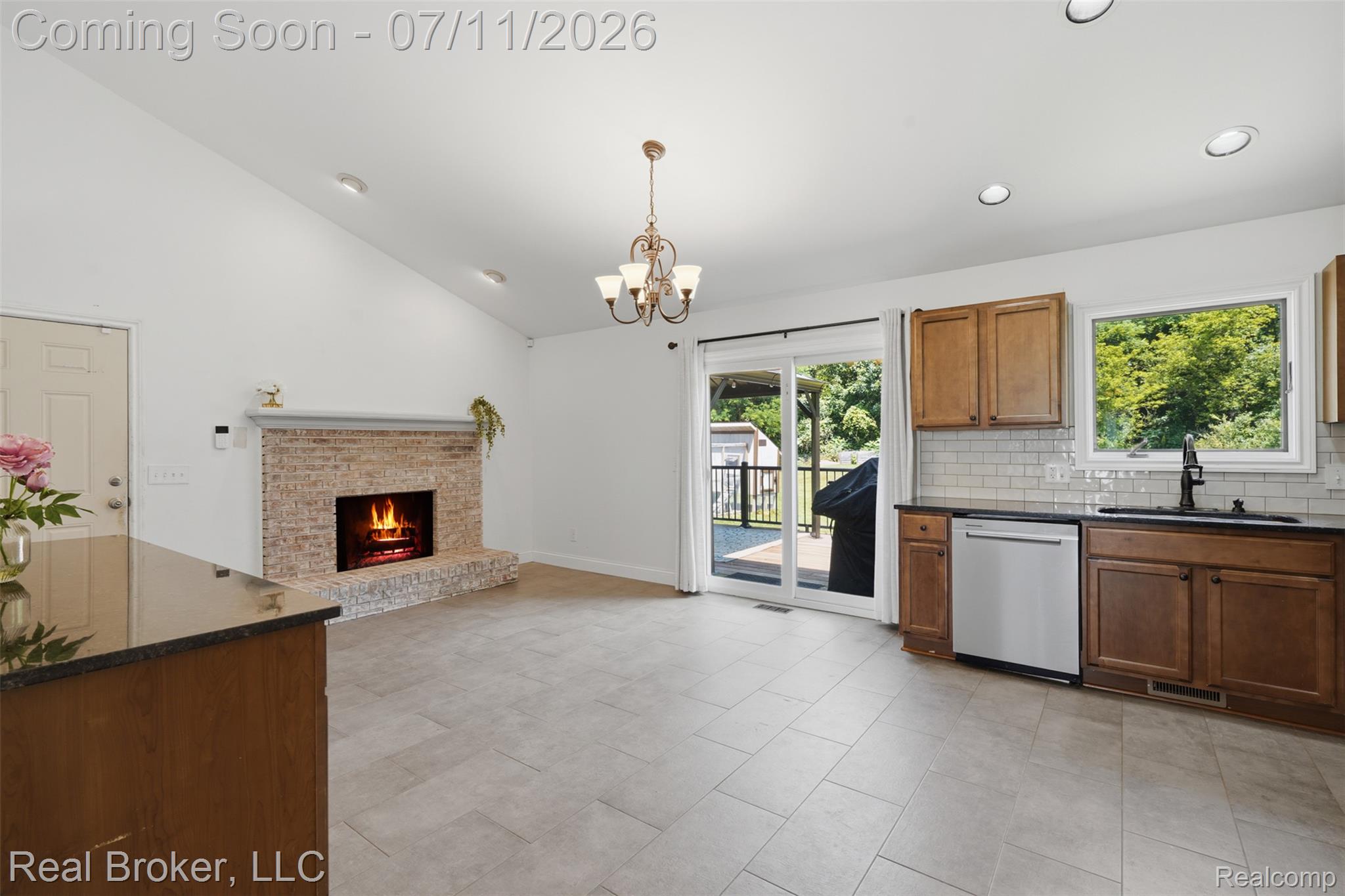 1050 West Brocker Road Metamora, MI 48455 - Photo 14 of 55 Kitchen and living area featuring a brick fireplace, vaulted ceiling, and light-toned tile flooring