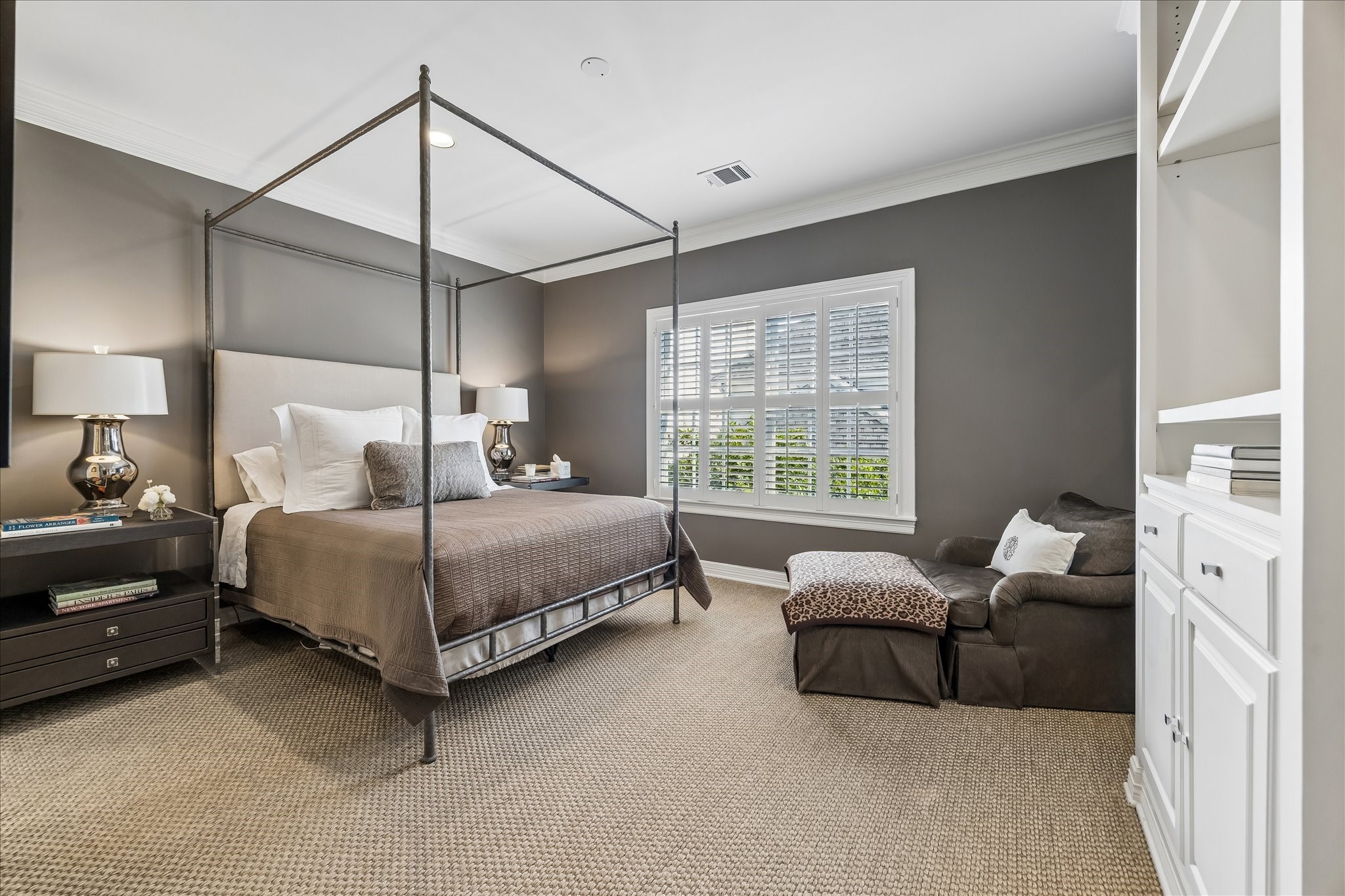 2627 Sutton Court Houston, TX 77027 - Photo 21 of 34 Spacious secondary bedroom featuring seagrass carpet, built-in shelving, and a rich, soothing paint palette that creates a warm and calming atmosphere.