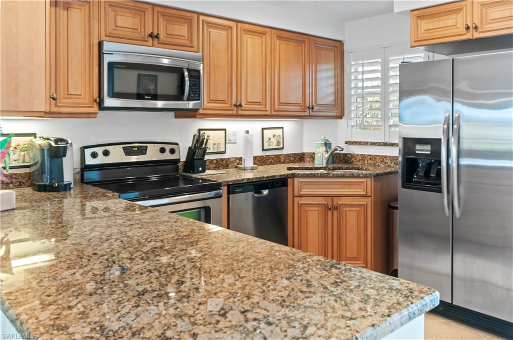 29 High Point Circle East, Unit 106 Naples, FL 34103 - Photo 12 of 42 a kitchen with stainless steel appliances granite countertop a stove sink microwave and refrigerator