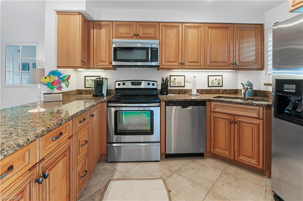 29 High Point Circle East, Unit 106 Naples, FL 34103 - Photo 13 of 42 a kitchen with granite countertop a stove top oven microwave and cabinets