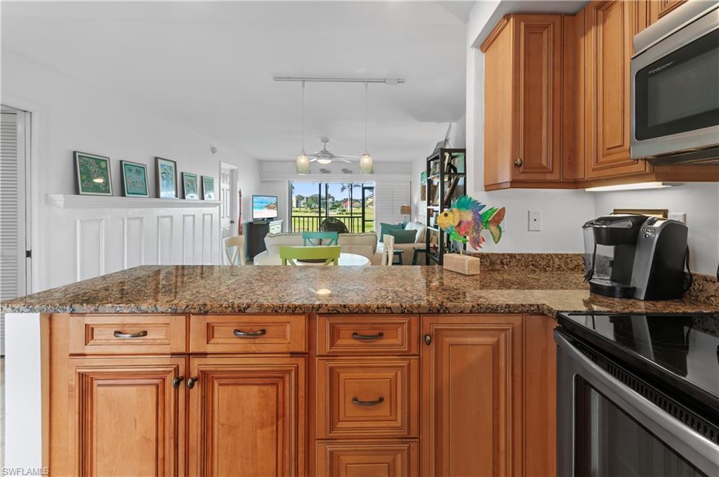 29 High Point Circle East, Unit 106 Naples, FL 34103 - Photo 14 of 42 a kitchen with granite countertop a sink a stove and cabinets