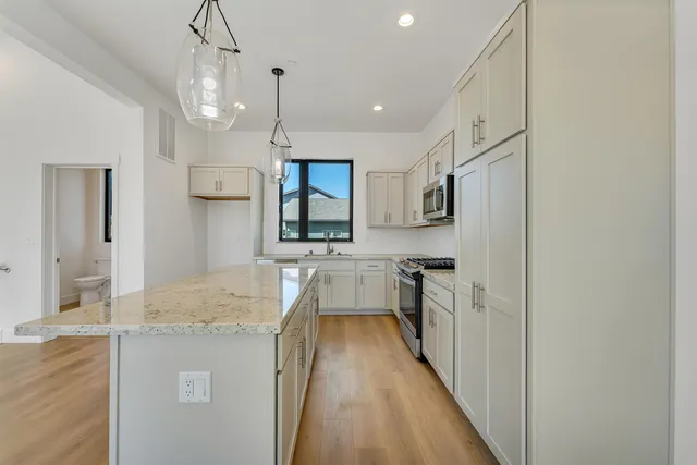 a kitchen with kitchen island granite countertop a sink a counter space stainless steel appliances and cabinets