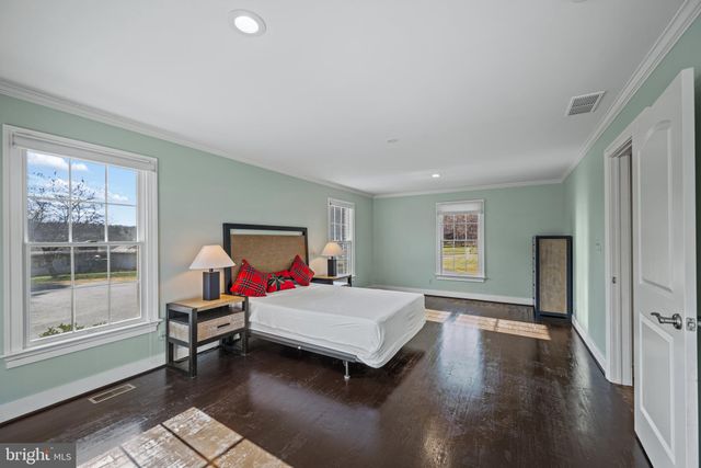 a view of a house next to a big yard with plants and large trees