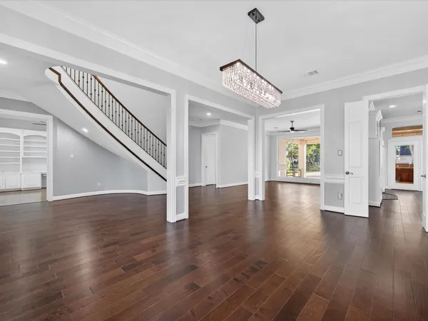 a view of a room with wooden floor chandelier and windows