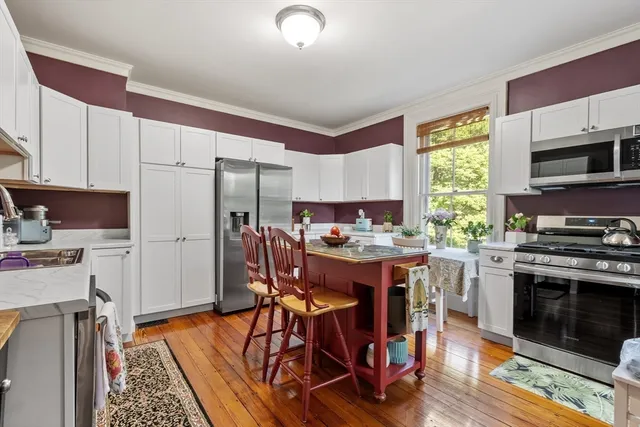 a kitchen with stainless steel appliances granite countertop a stove a refrigerator a kitchen island a sink dishwasher a dining table and chairs with wooden floor