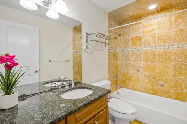 a bathroom with a granite countertop sink a mirror a bathtub and a toilet