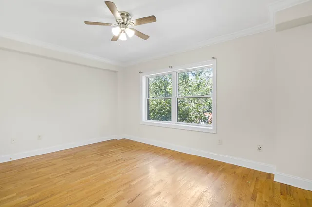 an empty room with a window and a fan