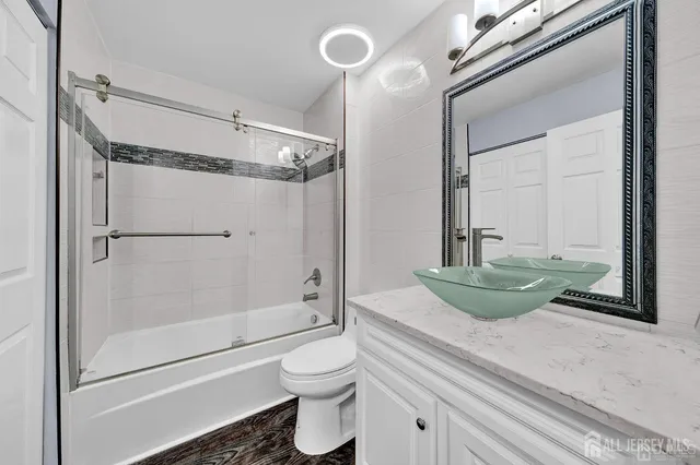 a bathroom with a granite countertop bathtub shower sink mirror and toilet