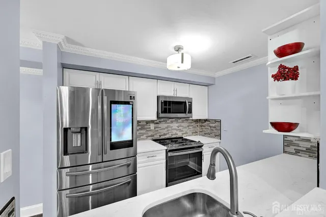 a kitchen with stainless steel appliances kitchen island granite countertop a refrigerator and a stove top oven